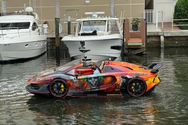 The Image of 2024 Watersports Car SERIES-L, vibrant design, floating on water near docked boats. - 0