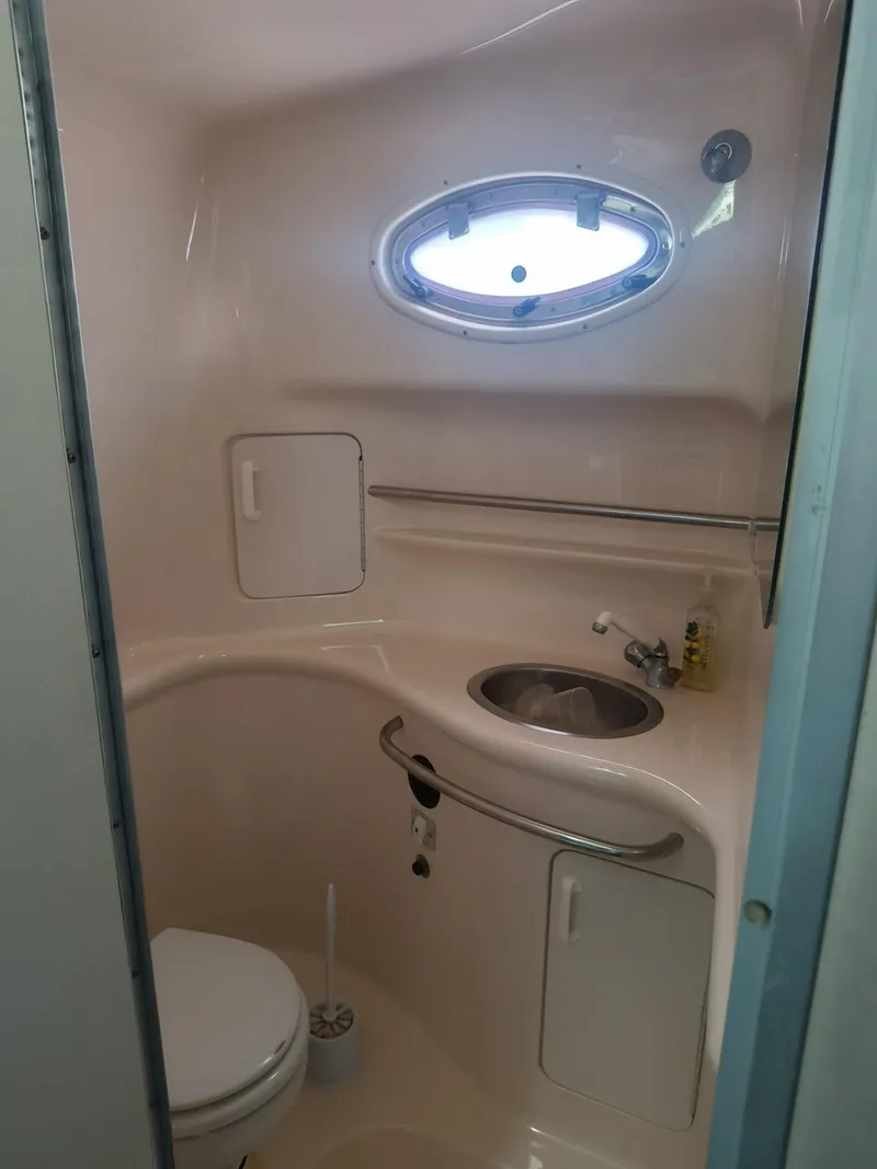 Slide: The Image of Compact bathroom in 1995 Sea Ray 330 Sundancer boat with sink, toilet, and porthole window. - 14