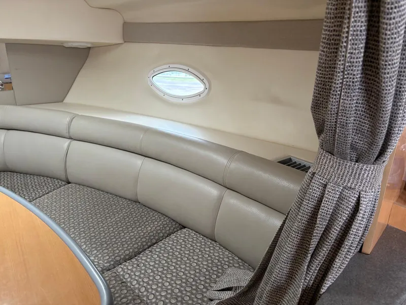Slide: The Image of 2004 Maxum 3100 SE interior with curved seating and porthole window. - 17