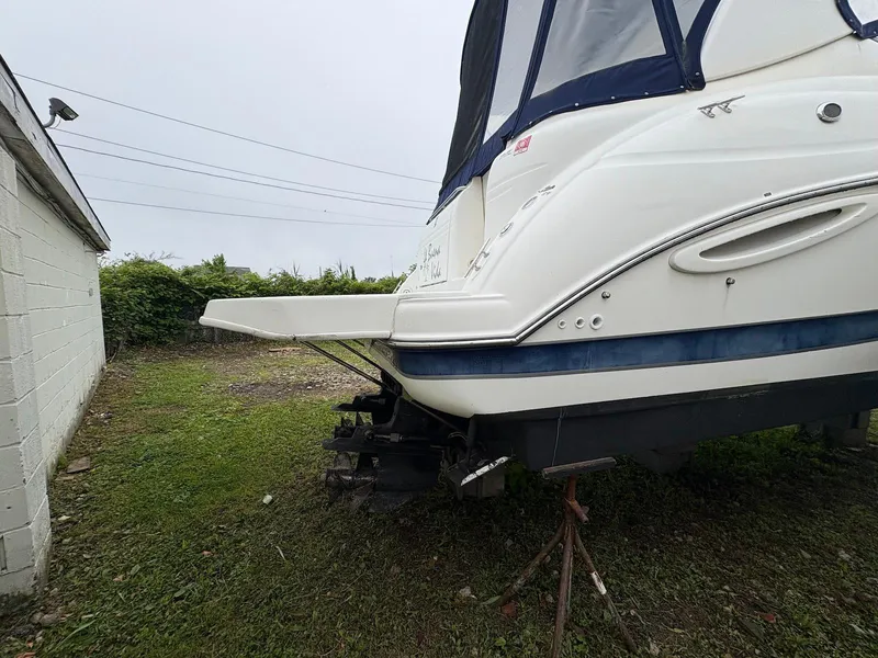 Slide: The Image of 2004 Maxum 3100 SE boat on land, near a white building, overcast sky. - 2