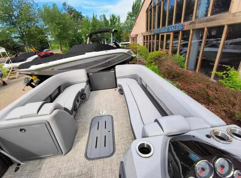 Slide: The Image of 2025 SunCatcher Fusion 322C boat interior with gray seating at a boat sales location. - 14