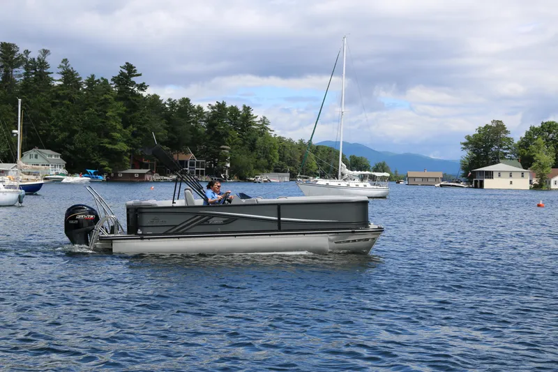Slide: The Image of 2025 SunCatcher Fusion 322C pontoon boat cruising on a scenic lake. - 2