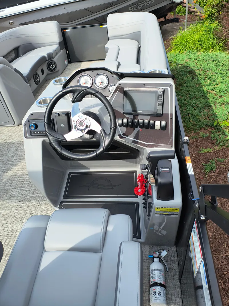 Slide: The Image of 2025 SunCatcher Fusion 322C boat cockpit with steering wheel, controls, and seating. - 21