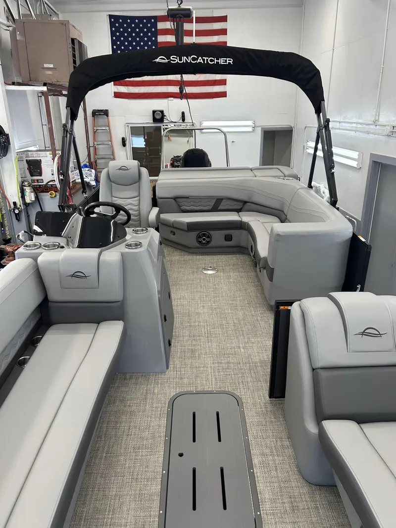 Slide: The Image of 2025 SunCatcher Fusion 322C pontoon boat interior with gray seating and American flag backdrop. - 5
