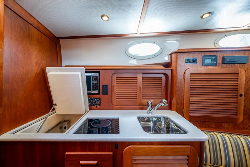 Slide: The Image of 2016 Hinckley Picnic Boat 37 MKIII galley with sink, stove, and wooden cabinetry. - 13