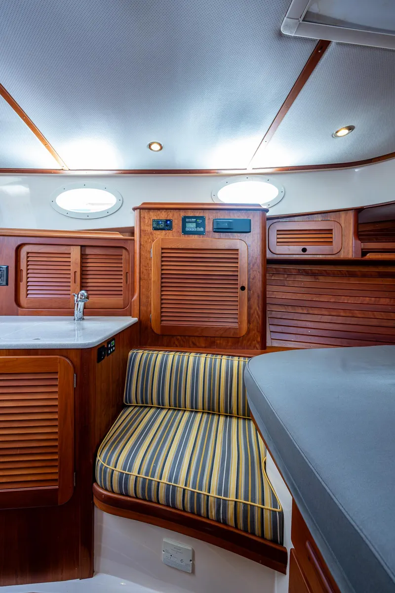 Slide: The Image of Interior of 2016 Hinckley Picnic Boat 37 MKIII with wood cabinetry and striped seating. - 14