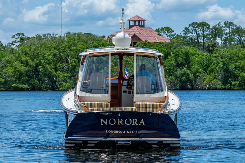 Slide: The Image of 2016 Hinckley Picnic Boat 37 MKIII cruising on a serene lake with lush greenery. - 2