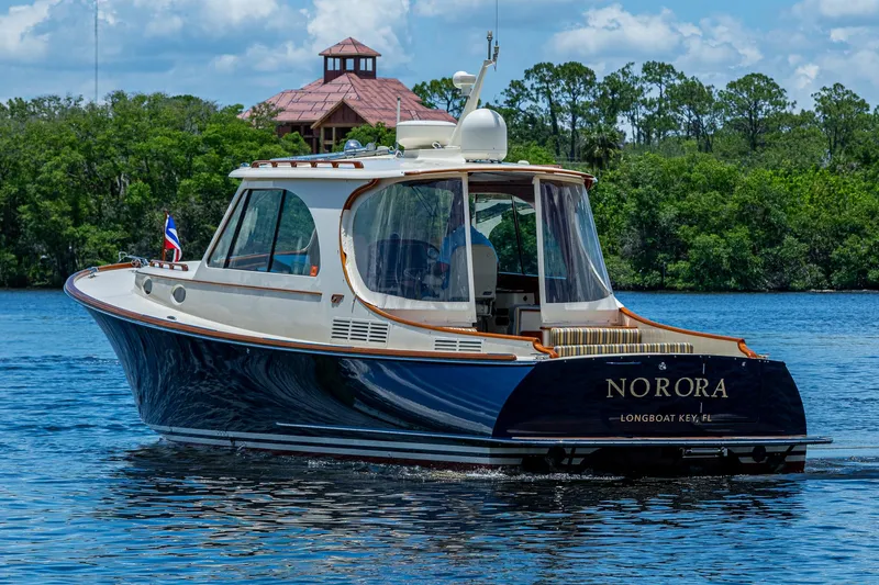 Slide: The Image of 2016 Hinckley Picnic Boat 37 MKIII cruising on a serene lake with lush greenery. - 24