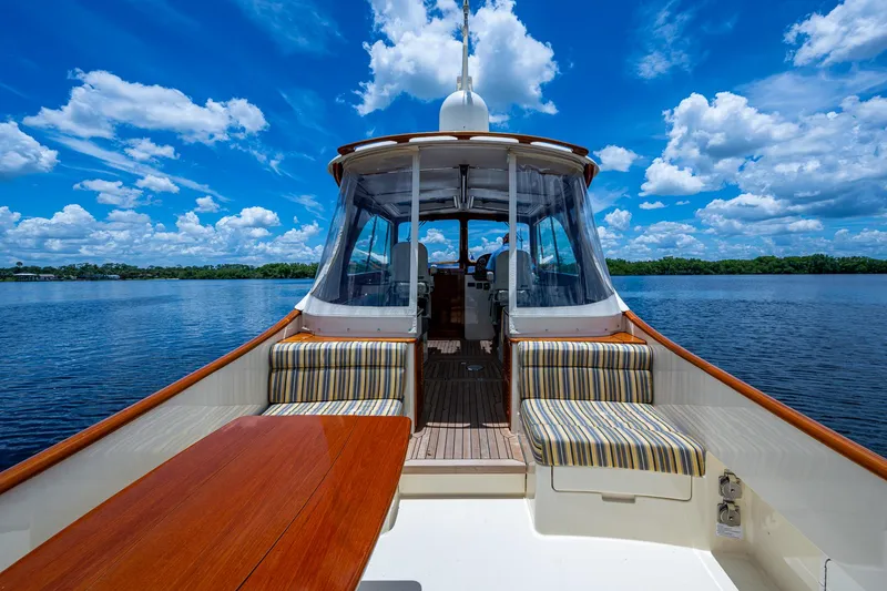 Slide: The Image of 2016 Hinckley Picnic Boat 37 MKIII on serene water, featuring striped seating and wooden table. - 3