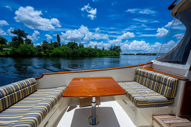 Slide: The Image of Hinckley Picnic Boat 37 MKIII, 2016, with striped seating and wooden table, on a scenic river. - 4