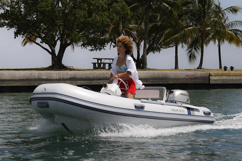 The Image of 2024 Highfield Classic 360 FCT boat cruising on water near palm trees. - 0