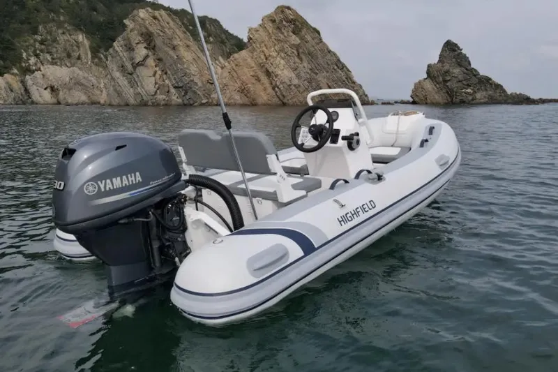 Slide: The Image of 2024 Highfield Classic 360 GT boat with Yamaha engine on calm water near rocky cliffs. - 1