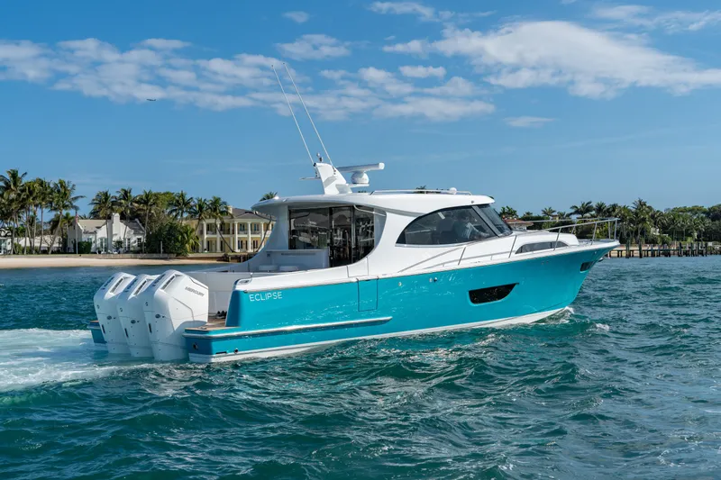 Slide: The Image of 2025 ECLIPSE 505 Shadow boat cruising on blue ocean near palm-lined shore. - 3