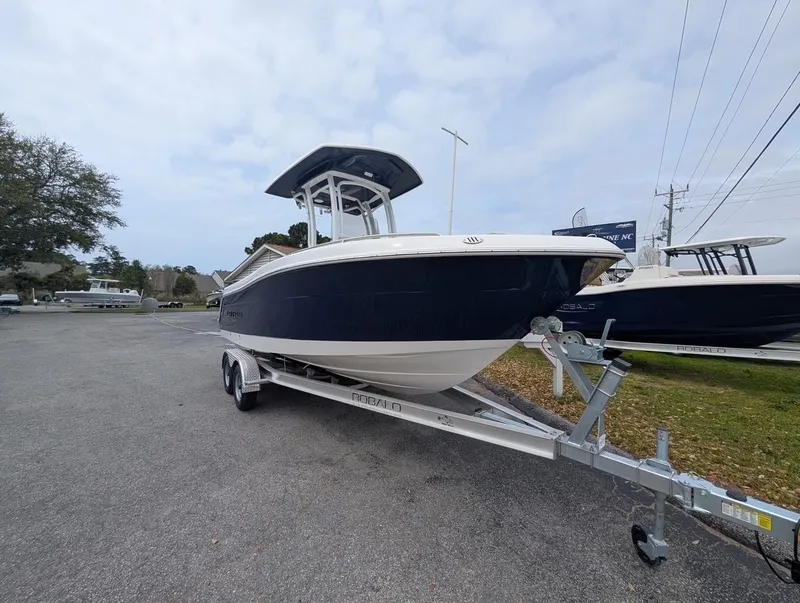 Slide: The Image of 2025 Robalo R222 Explorer boat on trailer, parked outdoors under cloudy sky. - 21