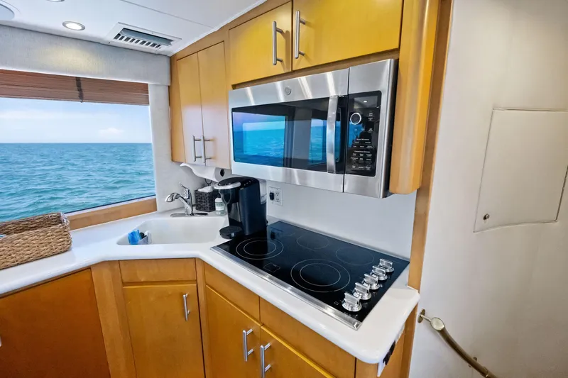 Slide: The Image of Kitchen area of 1998 Hatteras 60 Convertible yacht with ocean view, featuring modern appliances. - 36