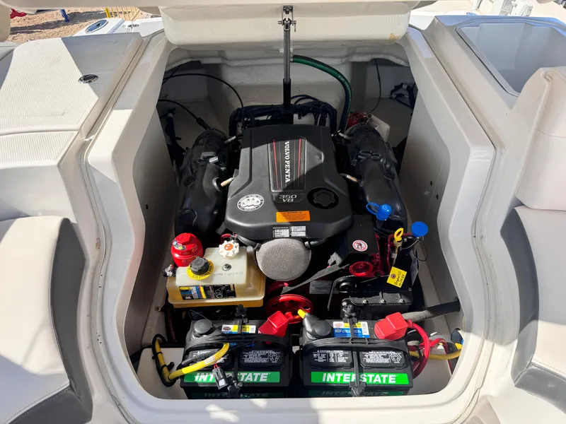 Slide: The Image of 2017 Chaparral 246 SSi boat interior with white and gray seating, parked outdoors. - 21