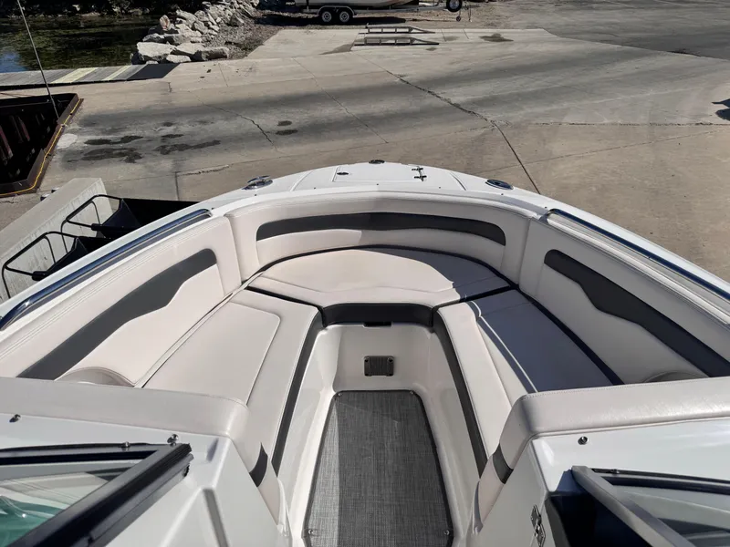Slide: The Image of 2017 Chaparral 246 SSi boat interior with seating and windshield, docked by a lake. - 31