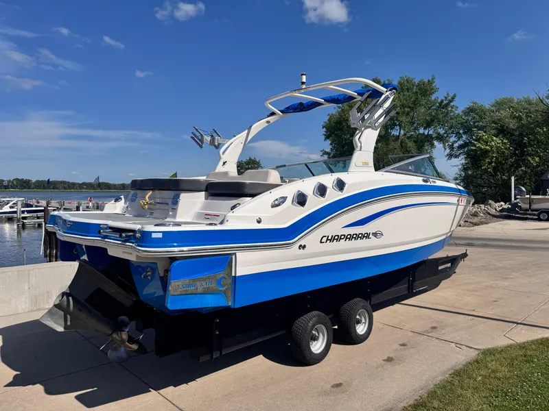 Slide: The Image of 2017 Chaparral 246 SSi boat on trailer, blue and white design, parked outdoors. - 5