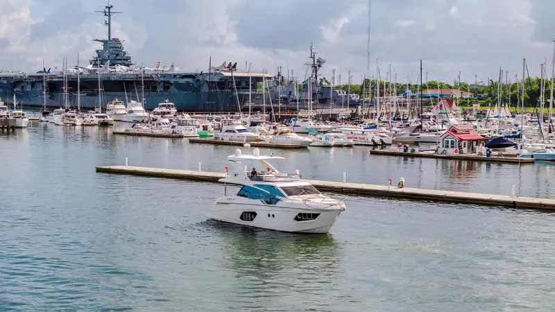 Slide: The Image of Luxurious 2017 Absolute 50 Fly yacht in a bustling marina with naval ship backdrop. - 38
