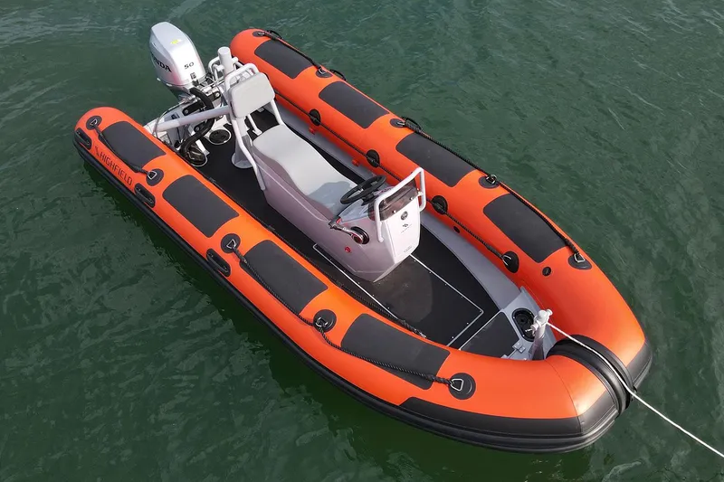 Slide: The Image of 2024 Highfield Patrol 420 inflatable boat on water, featuring orange and black design. - 2