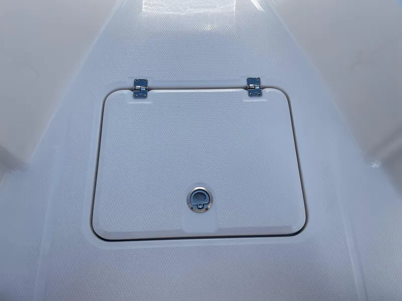 Slide: The Image of 2025 Robalo R230 Center Console storage compartment with secure latch and textured surface. - 20