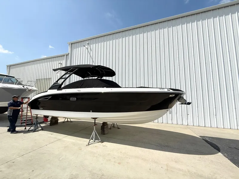 Slide: The Image of 2025 Sea Ray SDX 270 boat displayed outdoors, black hull, white trim, near a metal building. - 4