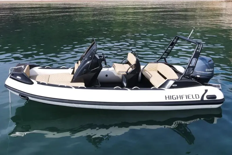 Slide: The Image of 2025 Highfield Sport 560 boat on calm water, featuring sleek design and Yamaha engine. - 2