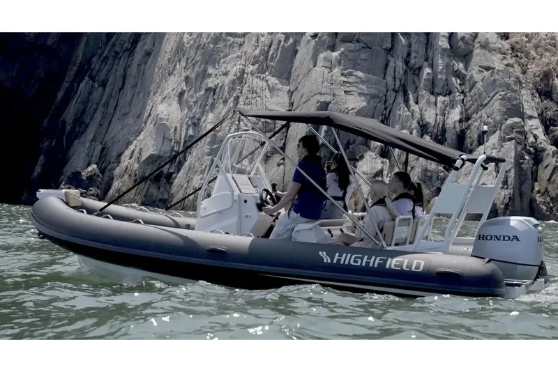 The Image of 2025 Highfield Sport 600 boat cruising near rocky cliffs with passengers onboard. - 0