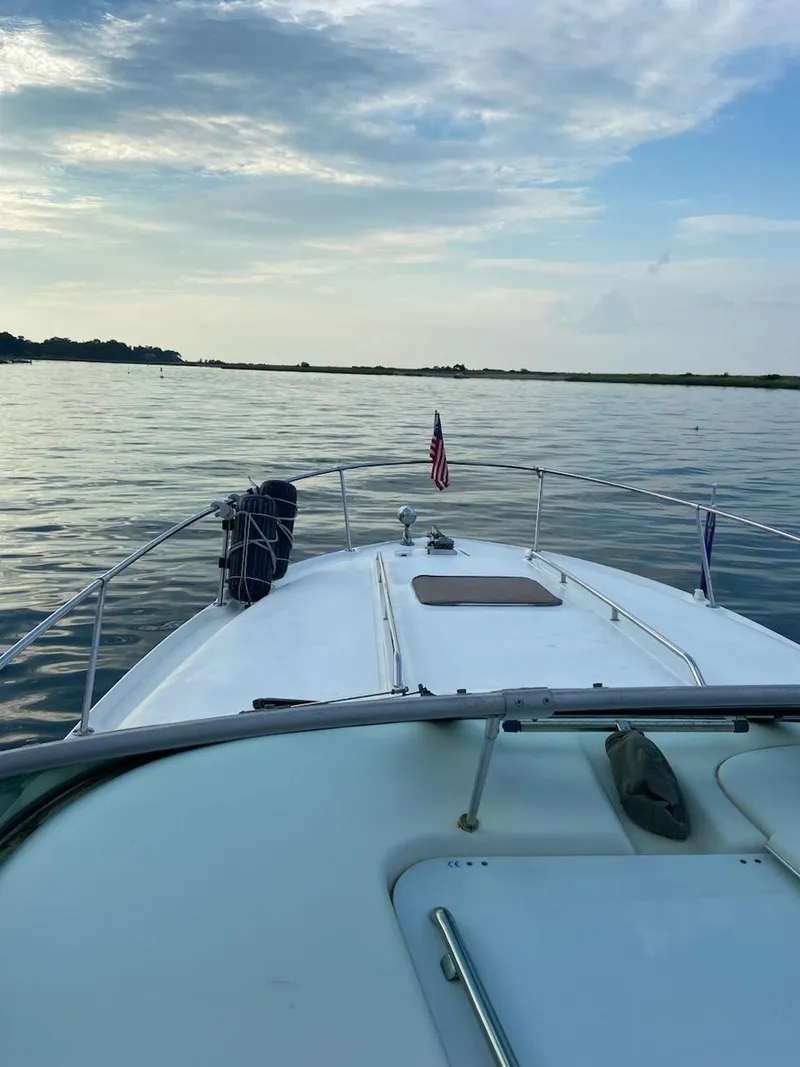 Slide: The Image of 1997 Sea Ray 290 Sundancer cruising on calm waters under a cloudy sky. - 2