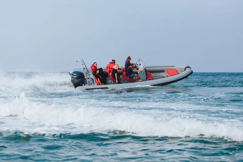 Slide: The Image of 2024 Highfield Patrol 760 boat speeding on ocean waves with passengers in life jackets. - 1