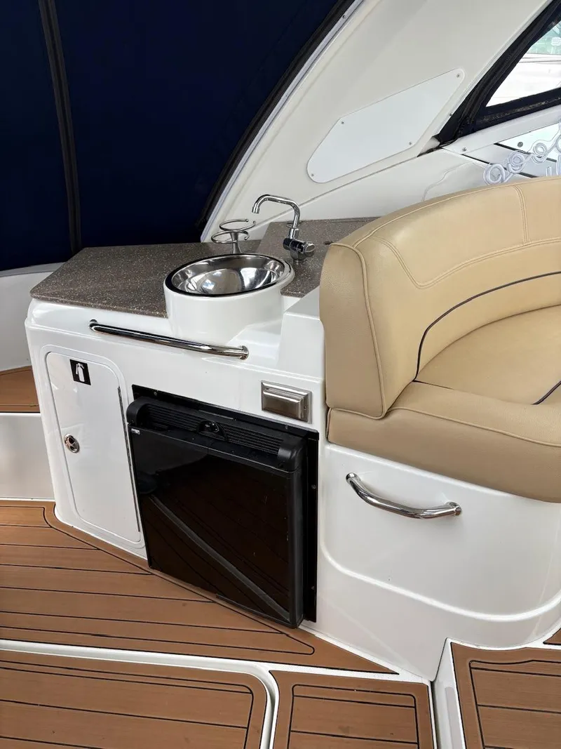 Slide: The Image of 2013 Cruisers Yachts 350 Express interior with sink, mini fridge, and seating. - 13