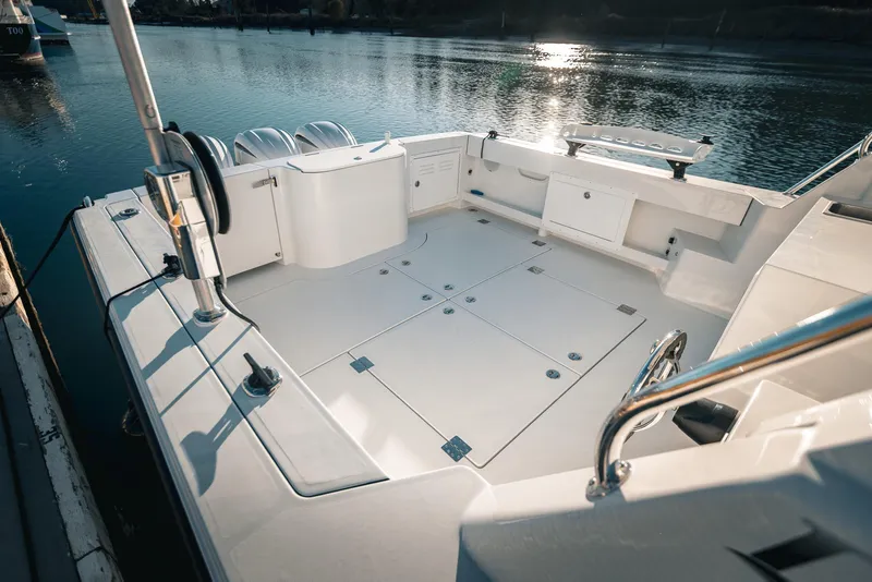 Slide: The Image of 2025 Lindell 38' boat deck with storage compartments, docked by calm water. - 7
