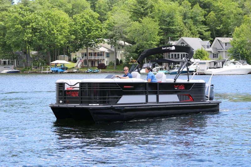 Slide: The Image of 2025 SunCatcher Elite 324 RC pontoon boat cruising on a scenic lake. - 0