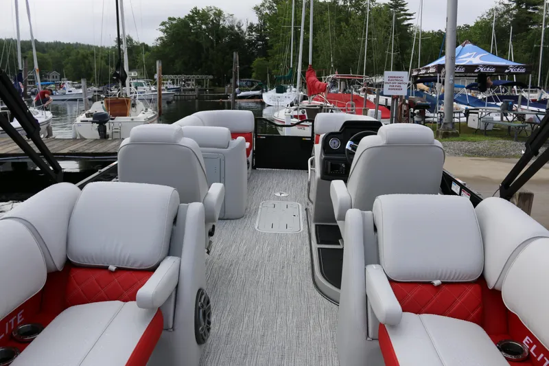 Slide: The Image of 2025 SunCatcher Elite 324 RC pontoon boat interior with plush seating at marina. - 1