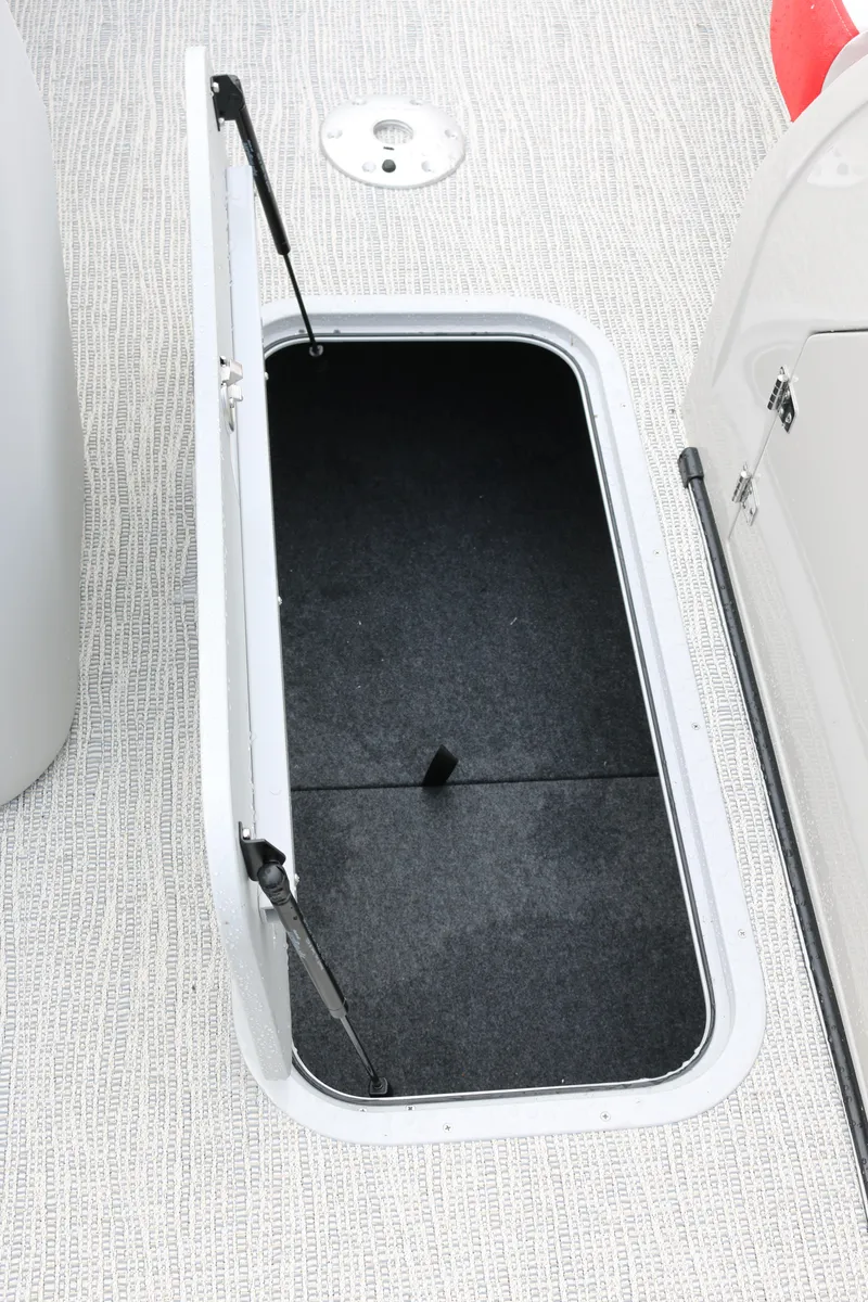 Slide: The Image of Open storage compartment on 2025 SunCatcher Elite 324 RC boat, featuring carpeted interior. - 19