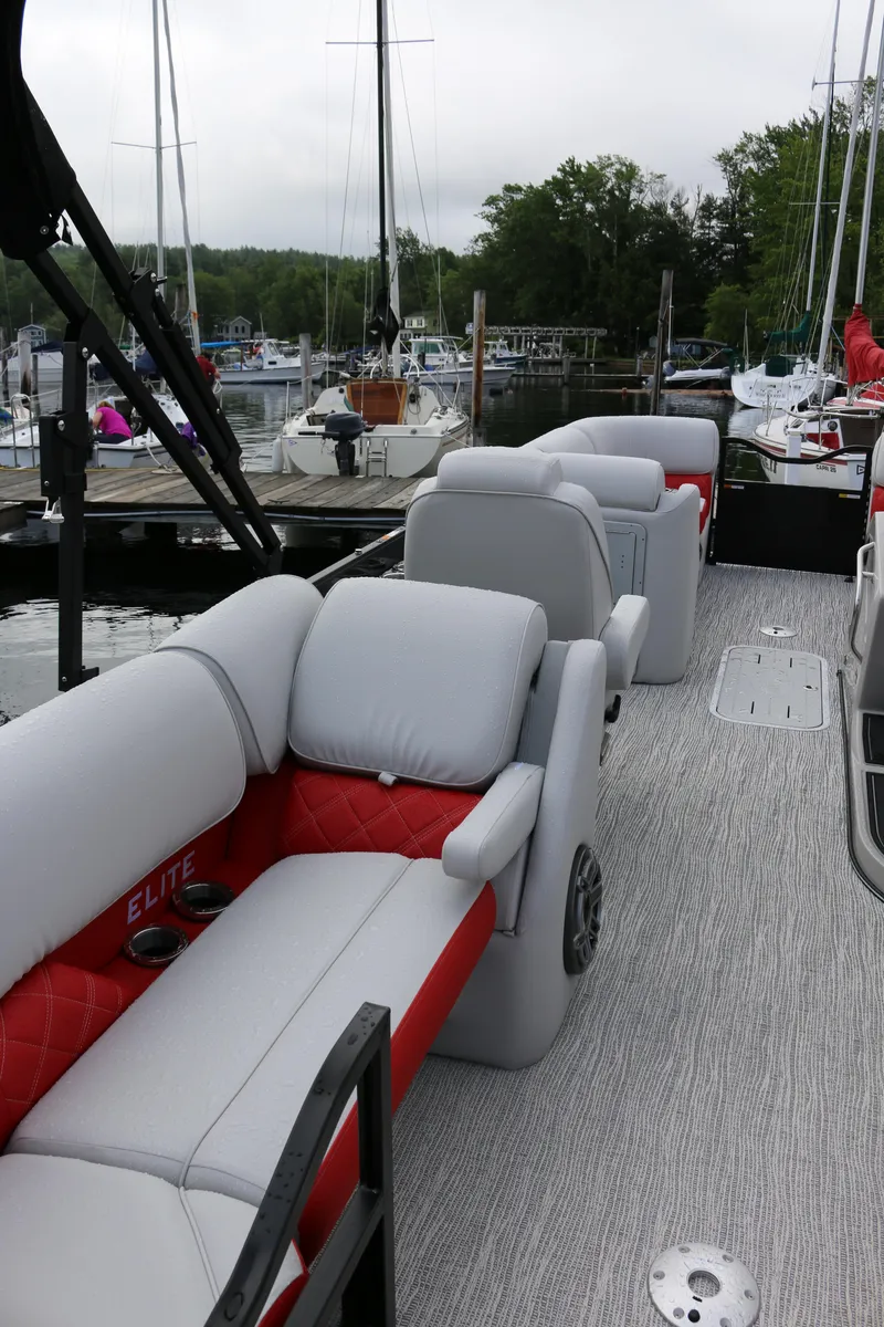 Slide: The Image of 2025 SunCatcher Elite 324 RC pontoon boat with luxurious seating at a marina. - 2