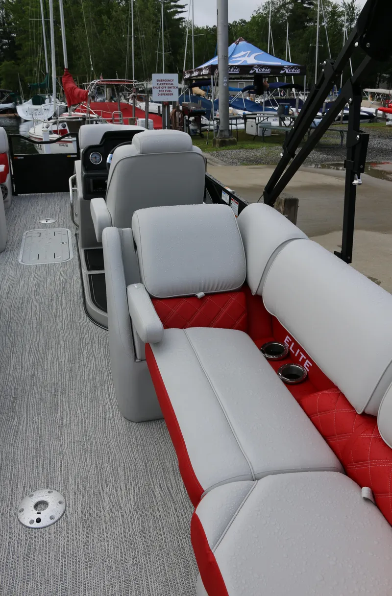 Slide: The Image of 2025 SunCatcher Elite 324 RC boat interior with gray and red seating, docked at marina. - 3