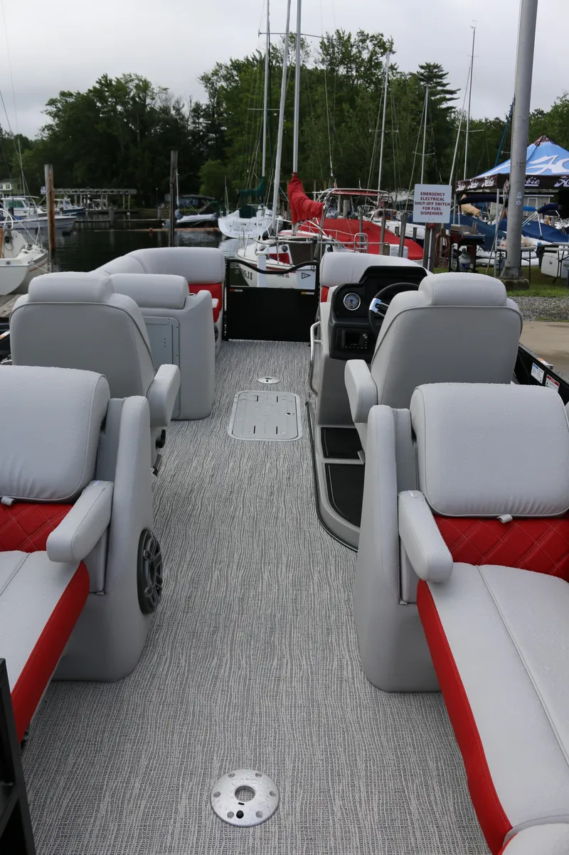 Slide: The Image of 2025 SunCatcher Elite 324 RC pontoon boat interior with gray and red seating, docked at marina. - 32