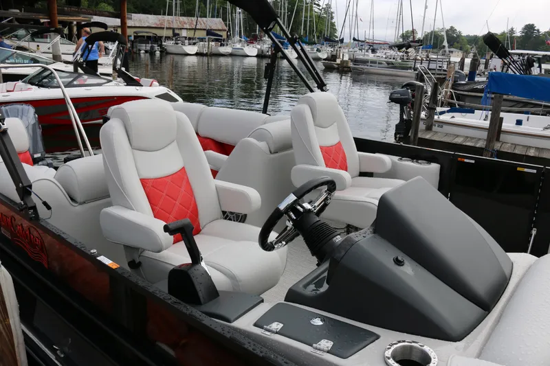 Slide: The Image of 2025 SunCatcher Elite 324 RC boat interior with red and white seating at a marina. - 34