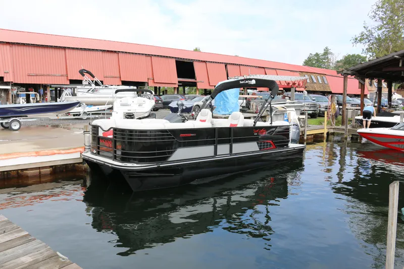 Slide: The Image of 2025 SunCatcher Elite 324 RC pontoon boat docked at marina with red-roofed buildings. - 36
