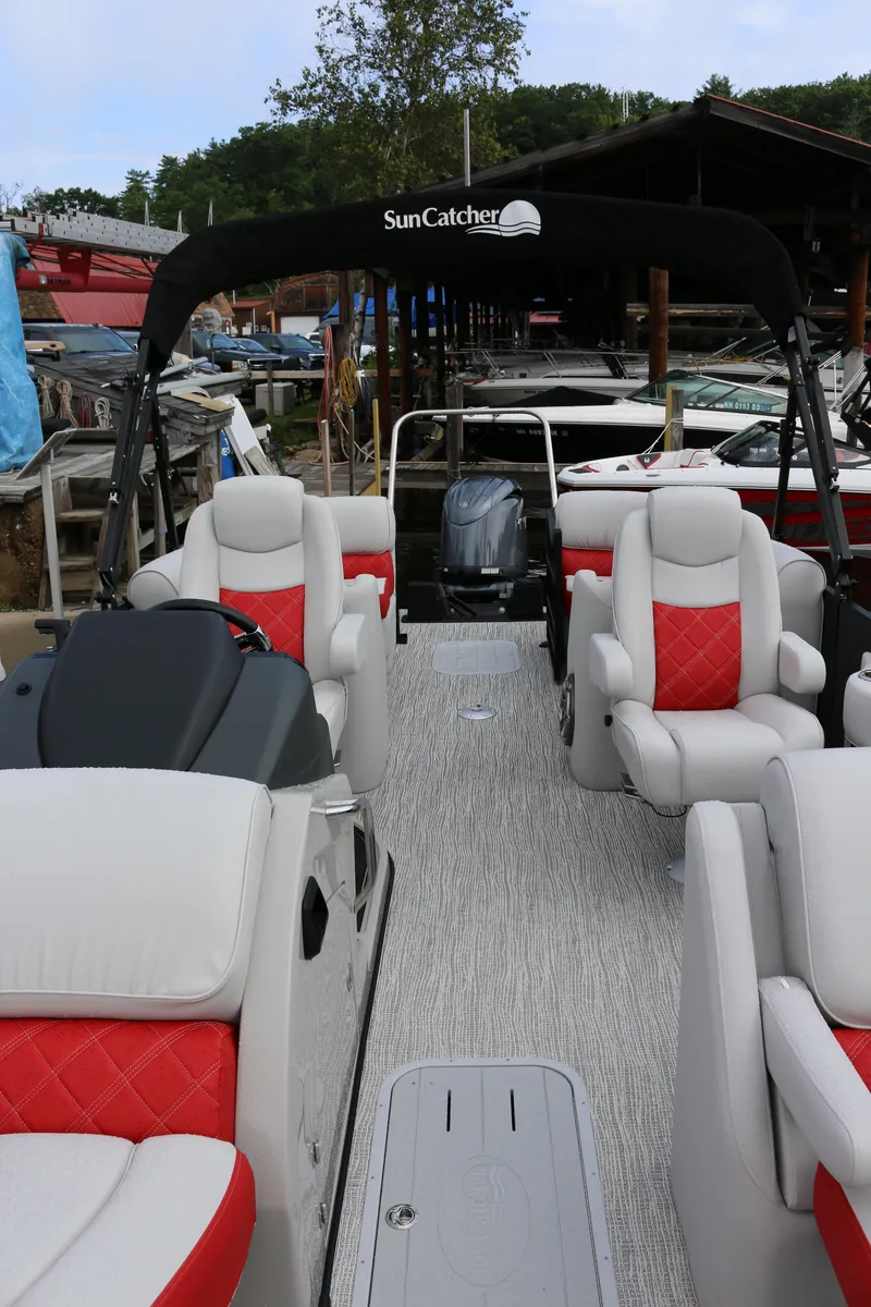 Slide: The Image of 2025 SunCatcher Elite 324 RC pontoon boat with red and white seating at a marina. - 4