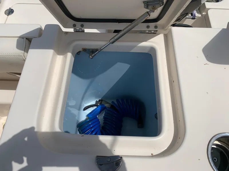 Slide: The Image of Open storage compartment on 2020 Grady-White 236 Fisherman boat with coiled blue hose. - 14