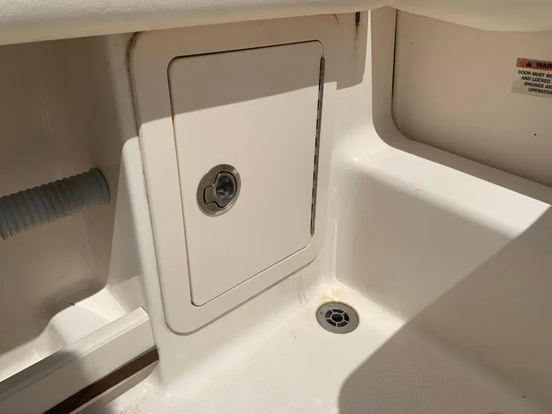 Slide: The Image of 2020 Grady-White 236 Fisherman boat storage compartment with drain and warning label. - 34