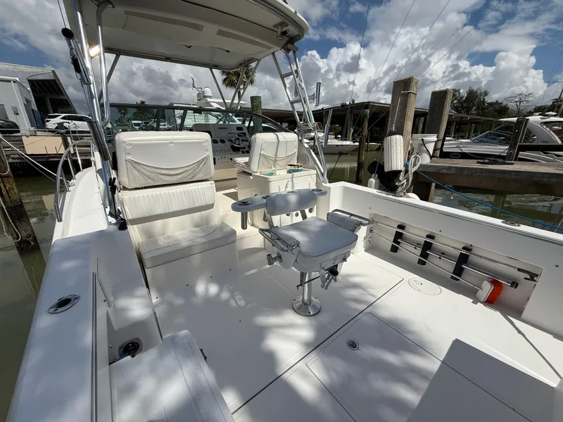 Slide: The Image of 2004 Stamas 320 Express boat interior with seating and fishing rod holders at a marina. - 11