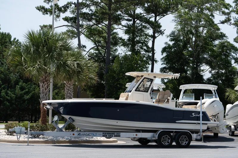 The Image of 2026 Scout 260 LXF boat on trailer, parked near palm trees. - 0