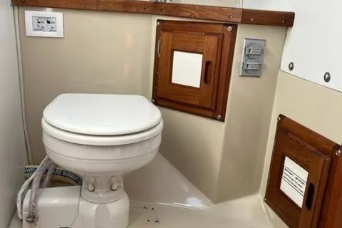 Slide: The Image of 1986 Catalina 30 boat bathroom with wooden cabinets and a white toilet. - 10