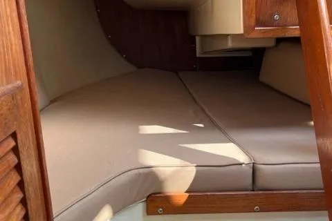 Slide: The Image of Interior cabin of a 1986 Catalina 30 sailboat with beige cushions and wooden accents. - 11