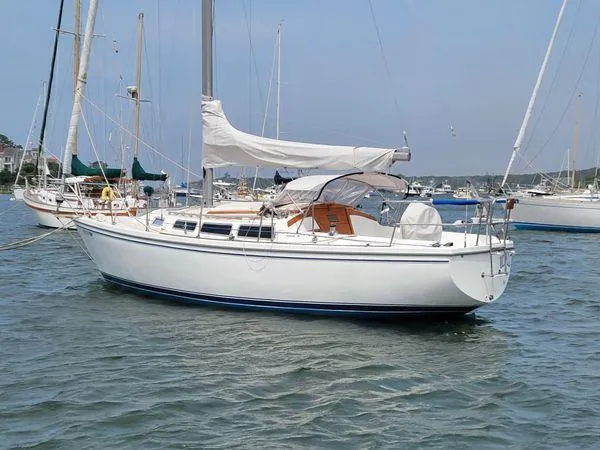 Slide: The Image of 1986 Catalina 30 sailboat anchored in a calm harbor, featuring a white hull and sails. - 16