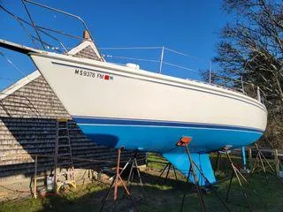 Slide: The Image of 1986 Catalina 30 sailboat on stands, blue hull, near wooden building. - 3