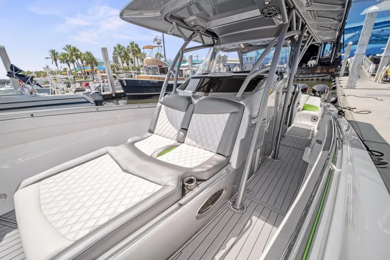 Slide: The Image of 2021 Nor-Tech 390 Sport Center Console boat with sleek seating and modern design at a marina. - 24